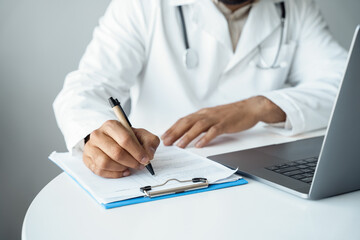 Mid-section arabian male doctor hands writing in patient checklist form
