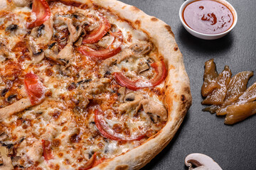 Fresh delicious Italian pizza with mushrooms and tomatoes on a dark concrete background