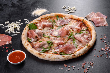 Fresh delicious Italian pizza with a prosciutto on a dark concrete background