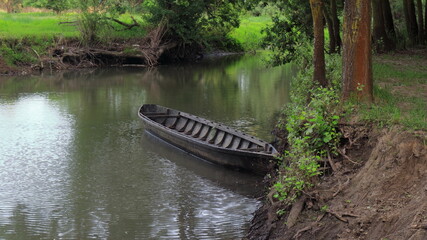 
A picturesque landscape with a forest river and a beautiful old wooden boat near the shore.