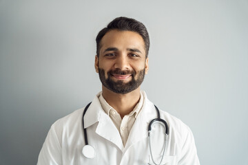 Headshot portrait of smiling doctor looking at camera over studio background