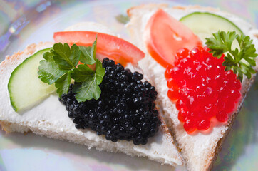 Sandwich with red and black caviar, butter, parsley and cucumber. Birthday and holiday tables.
