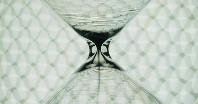 Transparent hourglass on background of bokeh lights. End of time cycle.