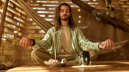 Front view of a man meditating wearing white T-shirt and shirt in stripes 