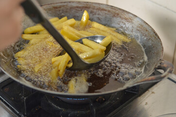 hand frying french fries in the frying pan
