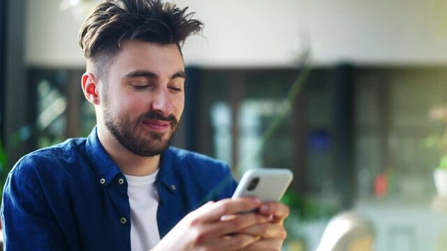 Closeup of young man using mobile phone indoors
