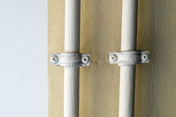 Two pipes are tied to the yellow wall.