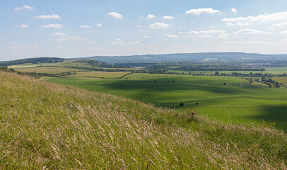 British spring landscape with hills, meadows and farms under blue cloudy sky.