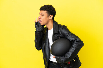 Young African American man with a motorcycle helmet isolated on yellow background shouting with mouth wide open to the side