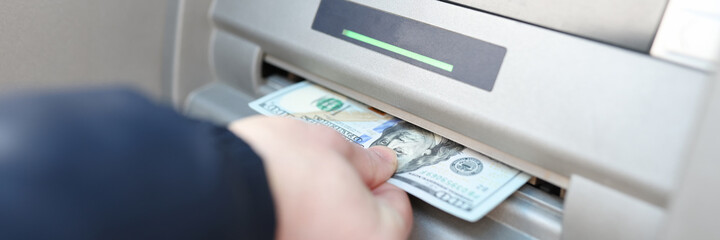 Man's hand takes out banknotes from an ATM