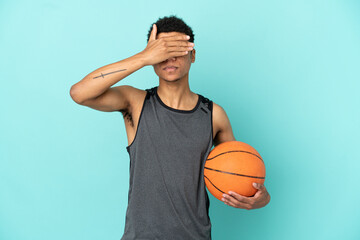 Obraz premium Basketball player African American man isolated on blue background covering eyes by hands. Do not want to see something