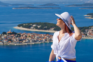 Beautiful tourist woman in a white straw hat on beautiful blue Adriatic Sea and cozy island background. Croatia during summer holiday. Luxury life at holiday at turquoise sea, ocean. Travel concept