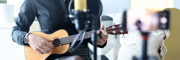 Woman plays ukulele, and records on smartphone