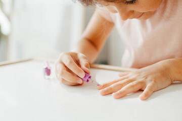 Obraz na płótnie Canvas Six year preschooler girl with interest paint on nails with nail polish