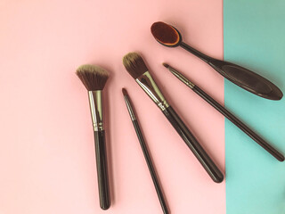 brushes lie on a bright background pink-blue background. brushes for makeup, skin, eyeshadows and eyelids. beauty with liquid and powdery textures