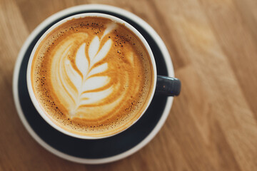 Tasty cappuccino in cup on wooden table