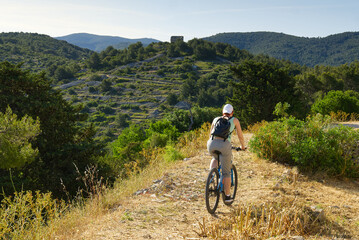 Fototapeta premium A woman cyclist rides along a mountain path on her mountain bike on a summer sunny day. activity. extreme sport