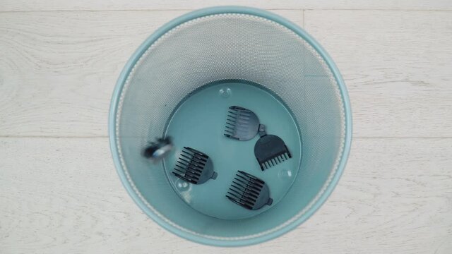 An old hair clipper with nozzles falls into the trash. Broken appliances
