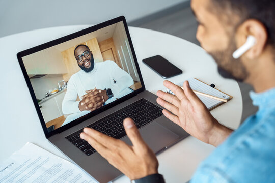 Afro american man talking using webcam internet connection, view over shoulder