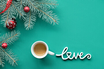 Obraz na płótnie Canvas Christmas background on turquoise, green textile with wooden text Love. Top view on fir twigs decorated with red glass baubles, traditional Xmas toys. Text love and coffee.