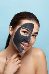 Beautiful young woman with mask for the face of black clay on clean fresh skin . Girl model beauty face care with moisturizer cosmetic mask. Facial treatment . Skin care