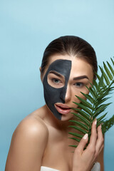 Beauty Woman Face Skin Care Mask. Portrait of a Beautiful Female with a Black Mask of Clay on Face .  Spa treatment . Girl Model with Moisturizer Cosmetic Mask.