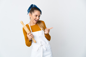 Young Lithuanian woman holding a rolling pin isolated on white background pointing finger to the...