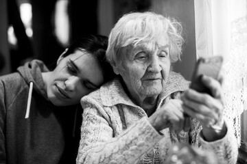 An old woman looks at a smartphone, with his daughter. Black and white photo.