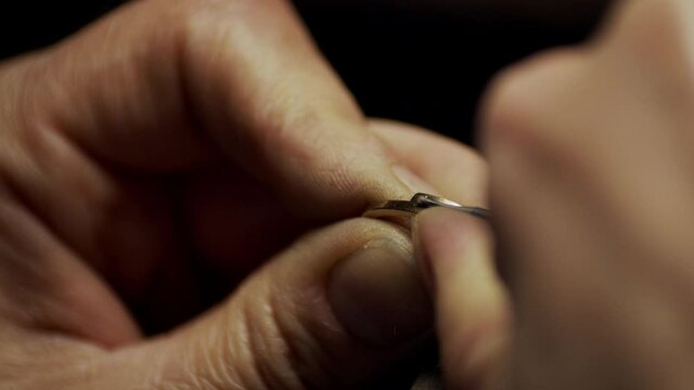 Jeweller drilling a small hole for a diamond in a golden engagement ring.