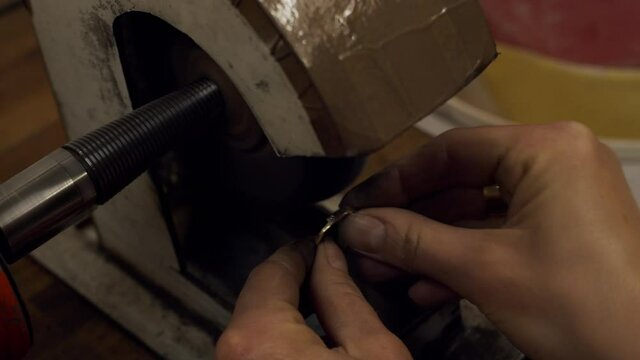Polishing a golden engagement ring using machine by a jeweller at a workshop.