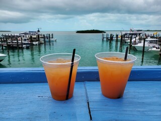 Orange rum drinks on blue deck overlooking marina in Bimini, Bahamas on overcast summer afternoon..