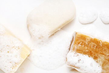 Soap bar and foam on white background, top view. Hygiene concept