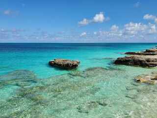 Fototapeta na wymiar Crystal clear water amidst rocks and sandy beaches of North Bimini's west coast in Bahamas.