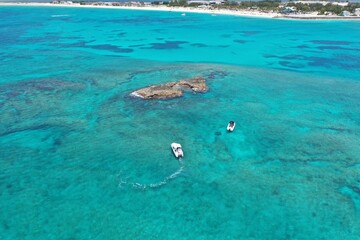 Aerial view of boats anchored near coral rocks off North Bimini, Bahamas on sunny summer afternoon.