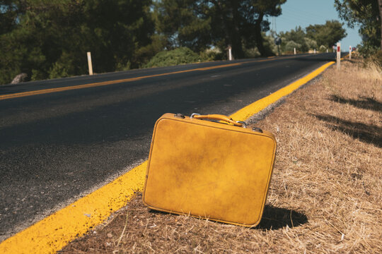 Close up shot of a yellow colored suitcase near the country roadside