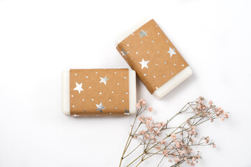 handmade craft soap in craft packaging and dried flowers on a white background