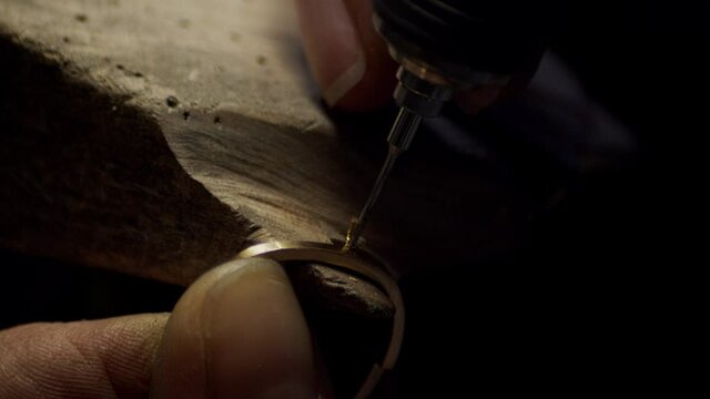 Closeup of a Jeweller drilling hole for a diamond in a golden engagement ring.