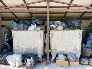 Bags of garbage are in the trash container. A lot of garbage was thrown into containers