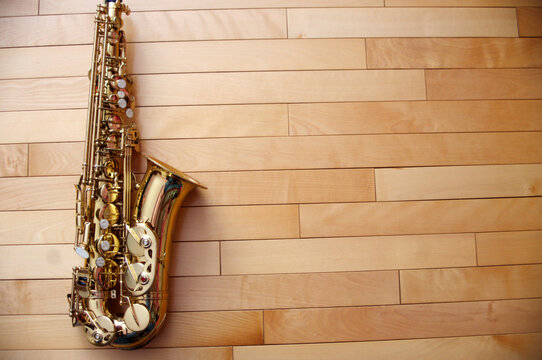 closeup of gold saxophone on wooden background copy space