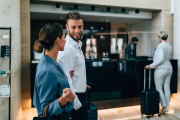 A young business couple arrives at the hotel and goes to the front desk to check in.