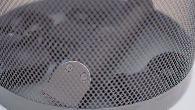 Defective and low-quality hair clipper with attachments lies at the bottom of the trash. View through the lattice of the trash can