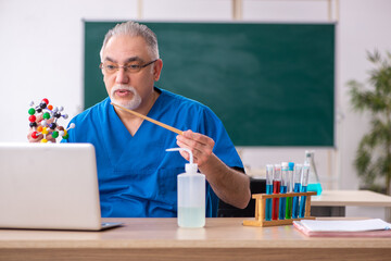 Old male teacher chemist in the classroom