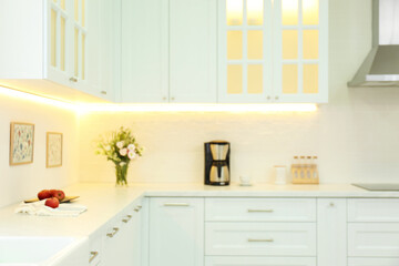 Fototapeta na wymiar Blurred view of modern kitchen interior with stylish furniture