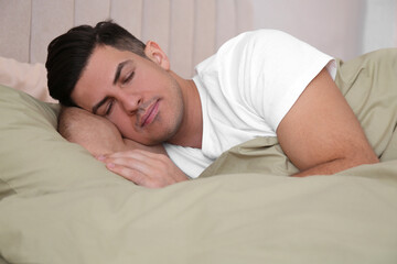 Fototapeta na wymiar Man sleeping in comfortable bed with green linens