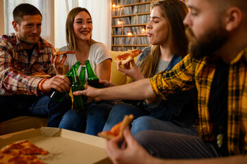 Group of friends on a house party drinking beer and eating pizza - obrazy, fototapety, plakaty