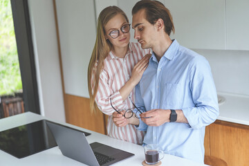 Young couple standing on the kitchen with laptop and working from home