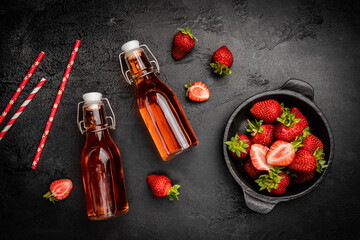 Refreshing summer drink with strawberry in a bottle on dark background, top view