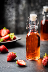 Refreshing summer drink with strawberry in a bottle on dark background