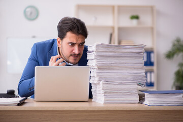 Young male employee unhappy with excessive work in the office