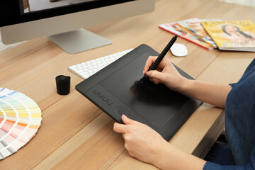 Professional designer working on graphic tablet at desk, closeup